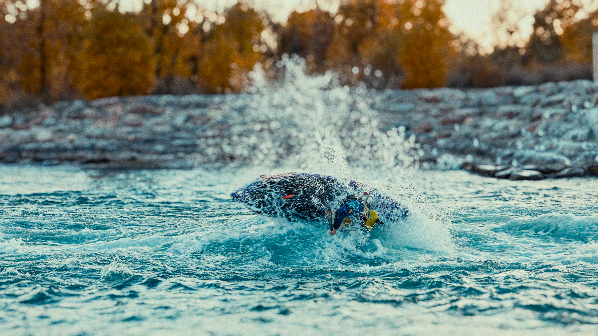 Packrafter executing a combat roll on a standing whitewater wave